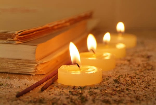 Quattro candele accese accanto a libri e bastoncini di incenso.