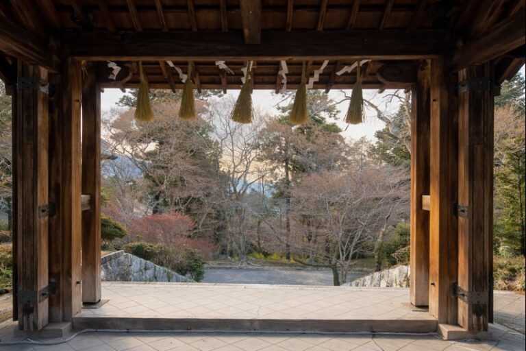 Ingresso del tempio Bishamondō a Kyoto in inverno, con travi in legno e corde rituali, affacciato su un giardino spoglio.